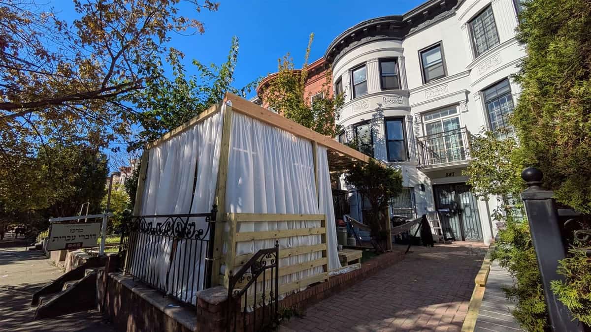 Finished front yard custom sukkah with white cloth wall covering and a wood frame
