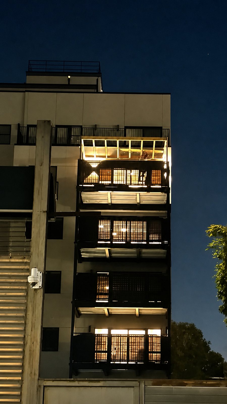 Exterior of a residential building with an illuminated upper-level pergola