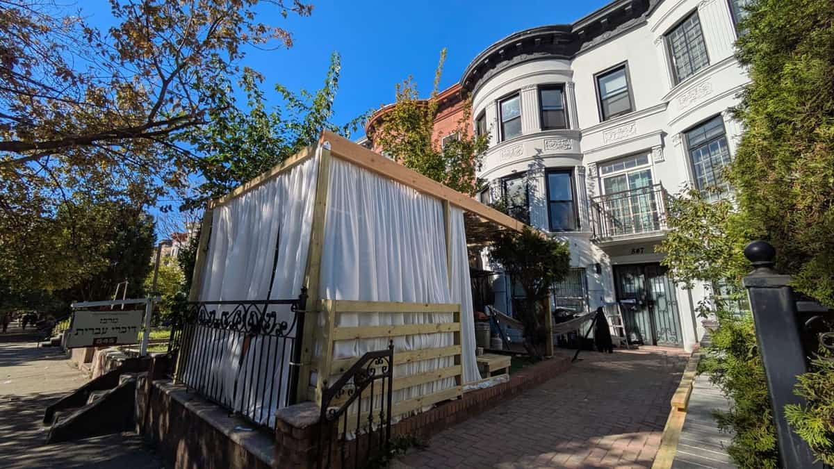 Freestanding pergola with white cloth side screening beside a row house