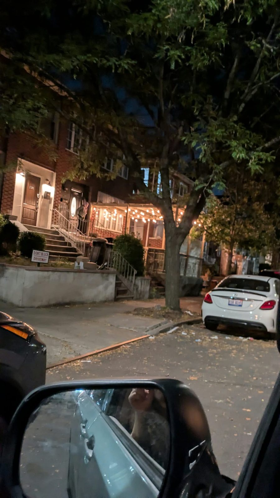 Wide street view of a lighted wood pergola in a front yard